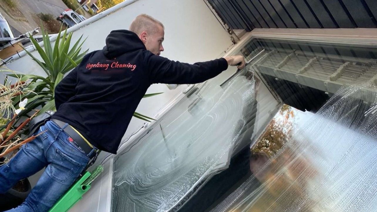 Vogelzang Cleaning aan het werk: hij trekt een ingezeept raam droog met de wisser
